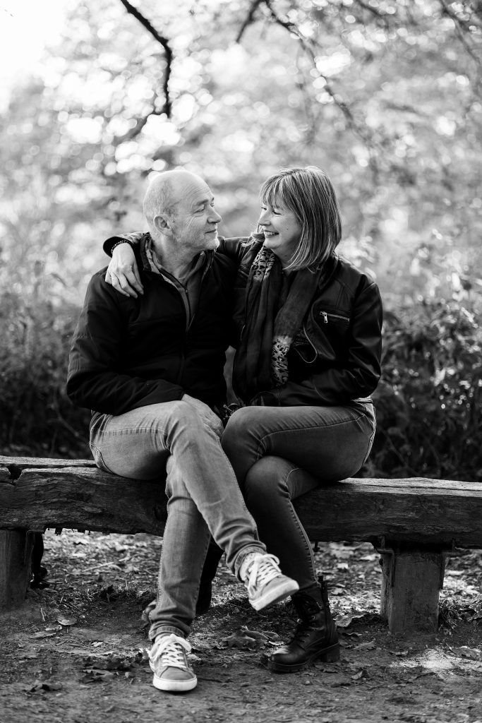 Shooting couple assis sur un banc en extérieur